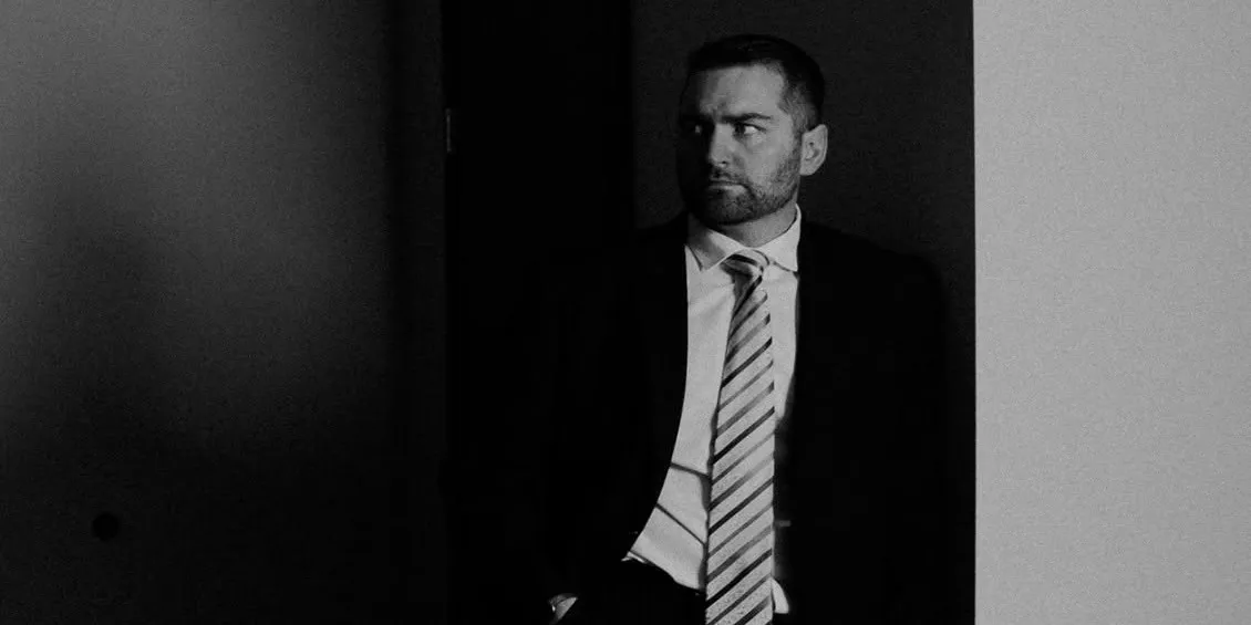 Brandon J. Grable, civil rights attorney in San Antonio, black-and-white portrait leaning against a hallway wall